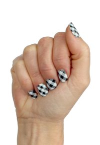 Black and white checkered nail design on a hand, featuring a mix of square patterns and teardrop shapes, with a matte finish.