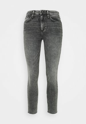 Wyblakłe czarne wąskie jeansy o średnim stanie, pięć kieszeni, z metalowym zapięciem. Gładka faktura denimu, dopasowana nogawka.