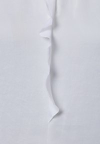 Witte stof met een verticale ruchesdetail langs de naad. Gladde textuur, lichtgewicht materiaal en een strak, minimalistisch ontwerp.