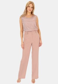 Top bez rękawów, w jasnoróżowym kolorze z subtelnym połyskiem; spodenki o wysokim stanie i szerokich nogawkach w pasującym różowym kolorze. Prosty design, gładka tekstura.