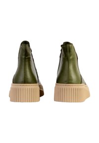 Botas de tobillo de cuero verde con una suela texturizada de color crema. Presentan un talón alto y un diseño acanalado en la base.