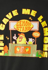 Tejido negro con un gráfico de un puesto de limones, donde hay un limón de dibujos animados con gafas de sol. El texto dice "LA VIDA ME DIO LIMONES" y "PUESTO DE LIMONES." El menú muestra los precios.