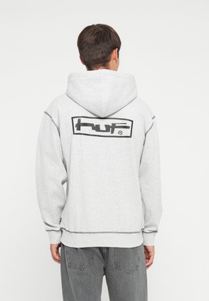 Grijze hoodie met een grote zwarte "huf" logo op de achterkant, en ribbels aan de mouwen en onderkant. Zacht materiaal met zichtbare stiksels.
