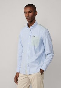 Camicia a righe blu chiaro con colletto button-down, dotata di tasca a quadretti verdi e un logo ricamato. Realizzata in tessuto intrecciato, maniche lunghe.
