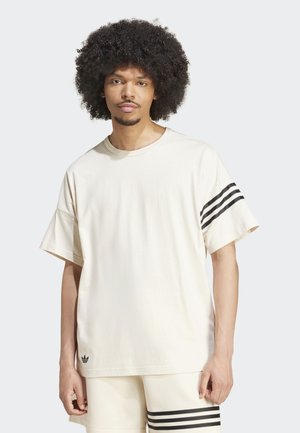 Ανοιχτό μπέζ βαμβακερό T-shirt με μαύρες οριζόντιες ρίγες στα μανίκια, στρογγυλή λαιμόκοψη και λογότυπο κοντά στο στρίφωμα. Χαλαρή εφαρμογή.