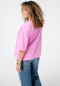 Overgroot roze katoenen t-shirt met korte mouwen, zijsplitten en een ronde hals, gecombineerd met blauwe denim jeans.