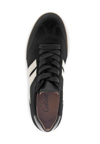 Sneaker nera con strisce bianche sui lati, lacci neri e soletta marrone marcata "Gabor," vista dall'alto su uno sfondo bianco.