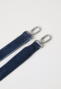 Denimové popruhy v tmavě modré a světle modré barvě s kovovými stříbrnými sponami. Obsahuje různé textury, včetně tkaného vzoru a hladkého povrchu.