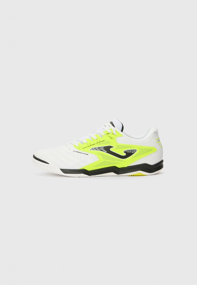 Hvit sportssko med neongule detaljer, svart såle, teksturert overdel, perforeringer for ventilasjon og kontrasterende lisser.