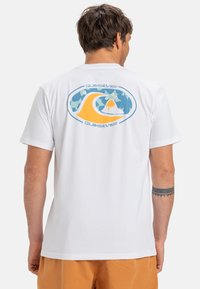 Hvit bomulls-T-skjorte med et fargerikt grafisk design på ryggen med bølgedesign, pyntet med blå og oransje toner. Korte ermer og standard passform.