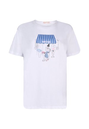 Wit T-shirt met een blauw gestreept luifelpatroon boven een vrouw die aan een cafétafel zit, een roze handtas vasthoudt en een bloemenboeket in de buurt heeft.