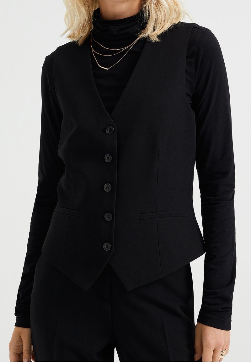 Svart skräddarsydd väst med v-ringning, sex knappar och två sidfickor. Slätt tyg med en åtsittande form och längre bakstycke.