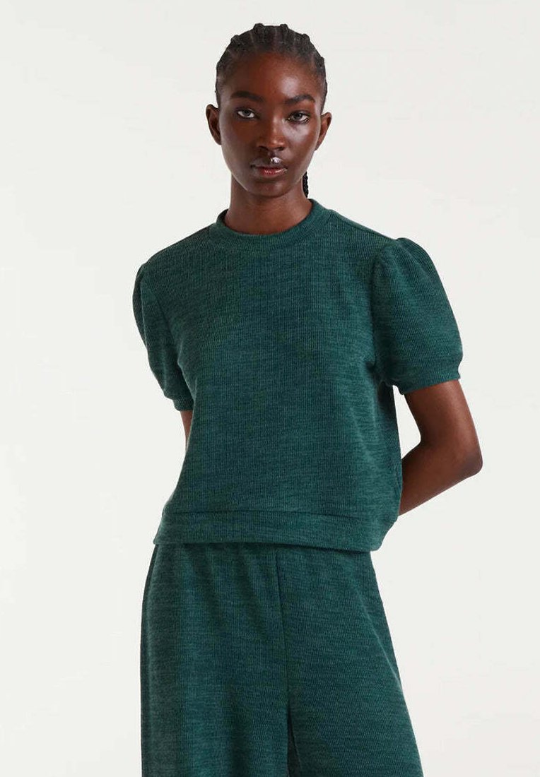 Top corto de manga corta con textura verde, cuello redondo y hombros abullonados, combinado con pantalones a juego para crear un look coordinado.