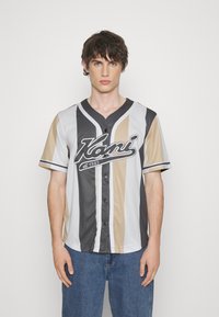 Kortermet baseballtrøye i grå, beige og off-white med vertikal stripemønster, knapplukking og brodert logo foran.