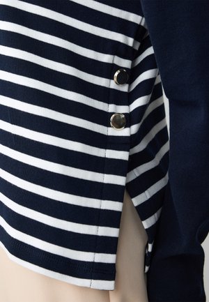 Gestreepte top in marineblauw en wit, van zacht stof, met metalen accenten aan de zijkant en sluitingdetails voor extra stijl.