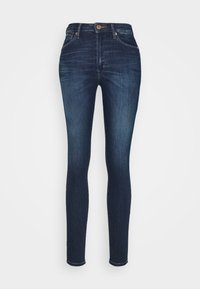 Jeans ajustados en denim azul oscuro, con una cintura de media altura, diseño de cinco bolsillos y costura en contraste. Textura suave con un ligero desvanecimiento.