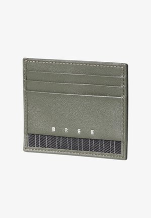 Portacarte sottile in pelle verde oliva con tre fessure per carte e una sezione in tessuto nero a righe nella parte inferiore.