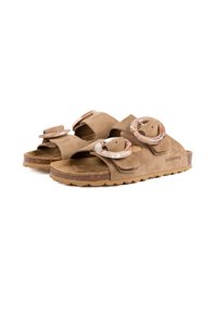 Sandales en daim beige avec deux sangles réglables, dotées de grandes boucles en marbre circulaires et d'une semelle en caoutchouc texturée.