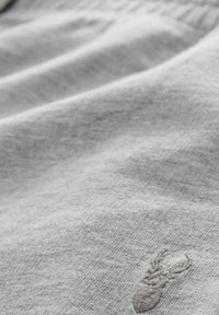 Tessuto di cotone grigio con una texture morbida, caratterizzato da un piccolo disegno ricamato di un'aragosta in un grigio leggermente più scuro.