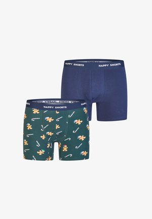Twee paar boxershorts voor heren, één effen marineblauw en één donker groen met een print van peperkoek en candycanes, beide met taillebanden waarop "HAPPY SHORTS" staat.