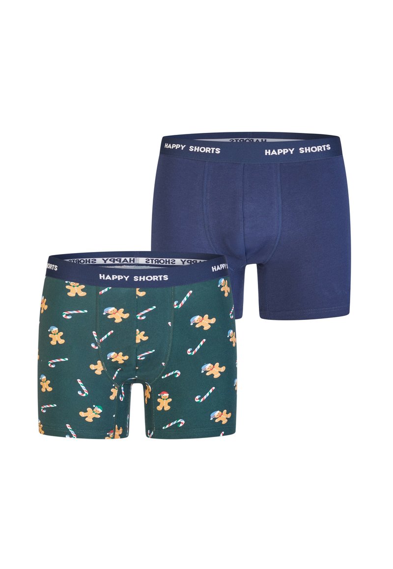 Twee paar boxershorts voor heren, één effen marineblauw en één donker groen met een print van peperkoek en candycanes, beide met taillebanden waarop "HAPPY SHORTS" staat.