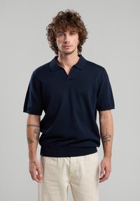 T-paita laivaston sininen, lyhythihainen, valmistettu neulottu kankaasta, jossa on V-pääntie, ribattua helmaa ja sileä pinta.