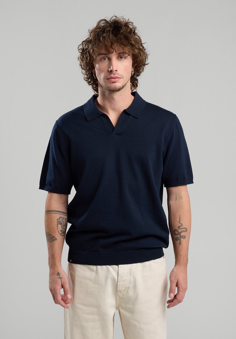 T-paita laivaston sininen, lyhythihainen, valmistettu neulottu kankaasta, jossa on V-pääntie, ribattua helmaa ja sileä pinta.