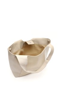 Krämfärgad läderhandväska med en slät yta, utrustad med ett enda handtag och en tryckknappsstängning, som öppnar mot en beige inredning.