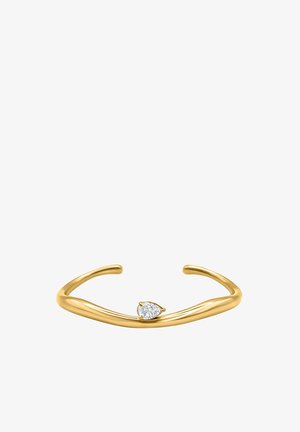 Bracelet manchette ouvert en or avec un petit diamant en forme de poire serti au centre sur un fond blanc.