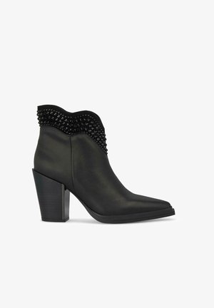 Schwarze Leder-Stiefeletten mit spitzer Zehenform, strukturiertem, gewelltem Kragen und Nietenakzenten. Fette Blockabsätze für zusätzliche Höhe.