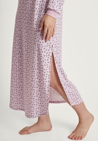 Robe da notte lunga rosa con motivo floreale, dotata di maniche lunghe e uno spacco laterale all'orlo. Tessuto morbido con una texture liscia.