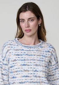 Pull en maille léger, de couleur blanche avec des rayures horizontales bleues et beiges. Doté d'un col rond et d'un motif texturé.
