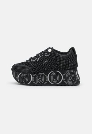 Czarny sneaker na platformie w białe grochy, z logo marki z boku i geometrycznym okrągłym wzorem na grubej podeszwie.
