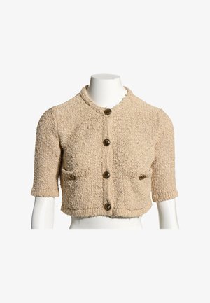 Cardigan beige texturé à manches courtes, col rond, quatre boutons devant et deux petites poches frontales, présenté sur un buste de mannequin blanc.