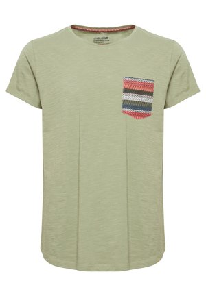 Camiseta de manga corta verde claro con cuello redondo y un bolsillo estampado colorido que presenta diseños en forma de zigzag en rojo, azul y blanco.