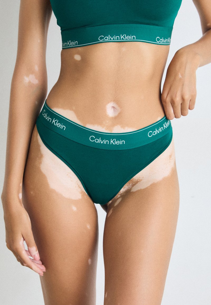 Groene katoenen bralette en bijpassende bikinislipjes met een Calvin Klein logo band. Gladde textuur, eenvoudig ontwerp en zonder patronen.