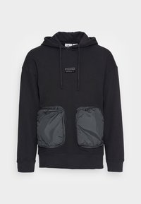 Svart adidas-hoodie med stora framfickor i nylon med dragkedja och huva med dragsko, som har en liten adidas-logotyp på bröstet.