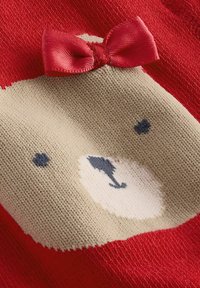 Czerwony sweter z motywem twarzy niedźwiedzia. Miękka dzianina, z beżowym niedźwiedziem i małą czerwoną satynową kokardką na górze. Subtelne niebieskie akcenty.