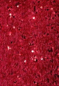 Tissu en sequins rouges avec une surface texturée, présentant des sequins circulaires scintillants et un aspect doux et superposé.