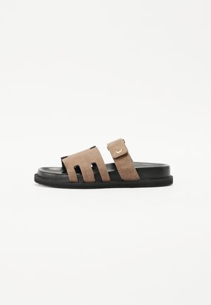Semišové skluzavkové sandály v hnědé a černé barvě. Obsahují dva široké výřezy na svršku a nastavitelného popruhu se zlatou sponou. Plochá podešev.