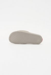 Semelle de chaussure avec une finition gris textured, dotée d'une semelle à motifs pour l'adhérence et d'un petit accent rouge au talon.