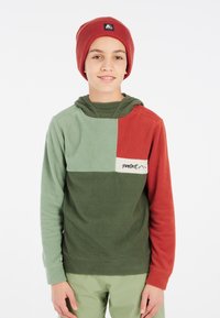 Fleece hættetrøje i grøn, rød og beige paneler; blød tekstur; broderet logo på brystet. Bruges med en matchende rød hue.