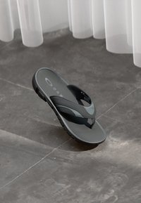 Chancla gris con un acabado suave y mate; cuenta con una correa ancha y una suela texturizada para mayor agarre. Acabada con un sutil logotipo en la plantilla.