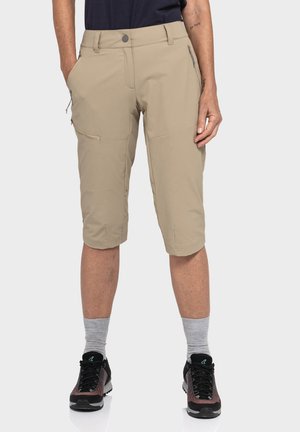 Beige knielange Shorts aus leichtem Stoff, mit mehreren Taschen und einem Knopfverschluss. Getragen mit grauen Socken und schwarzen Schuhen.