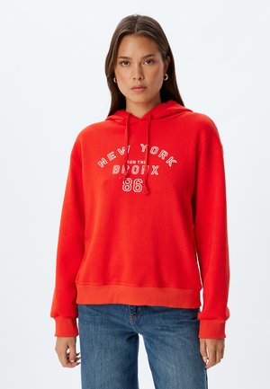 Felpa rossa in cotone con cappuccio regolabile, caratterizzata da un testo bianco che recita "NEW YORK BRONX 86." Fit rilassato con polsini e orlo a coste.