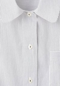 Chemise blanche à fines rayures verticales noires, trois boutons blancs, col pointu et une petite poche poitrine avec des rayures horizontales.