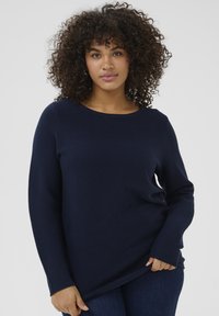 Navy blue ribbed long-sleeve top with a rounded neckline and relaxed fit, made of soft fabric, featuring a textured surface.