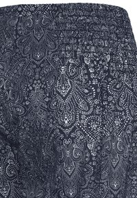 Tessuto blu navy con vita elasticizzata caratterizzata da intricati motivi paisley e floreali bianchi punteggiati.