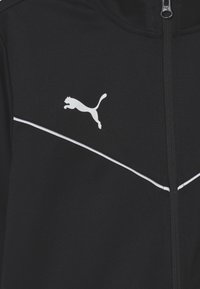 Giacca sportiva nera con dettagli bianchi e logo Puma. Presenta una zip completa, un colletto alto e un tessuto liscio e testurizzato.