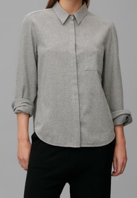 Grijze button-up shirt met lange mouwen gerold tot aan de ellebogen, met een enkele borstzak en een gladde, gestructureerde stof.